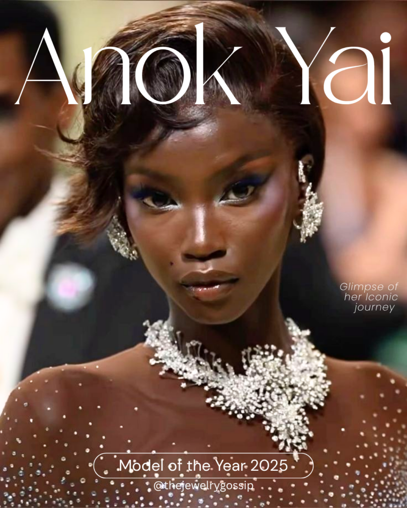 A close-up portrait of model Anok Yai on a fashion runway, wearing a shimmering crystal-embellished gown and an intricate diamond necklace with matching earrings. Her makeup is bold with dramatic eyeshadow, and her short, styled hair frames her face. Large elegant typography overlays the image, reading “Anok Yai” at the top and “Model of the Year 2025” at the bottom.