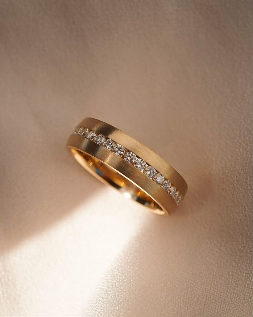 Men’s diamond engagement ring in brushed gold with channel-set diamonds, blending masculinity and luxury.