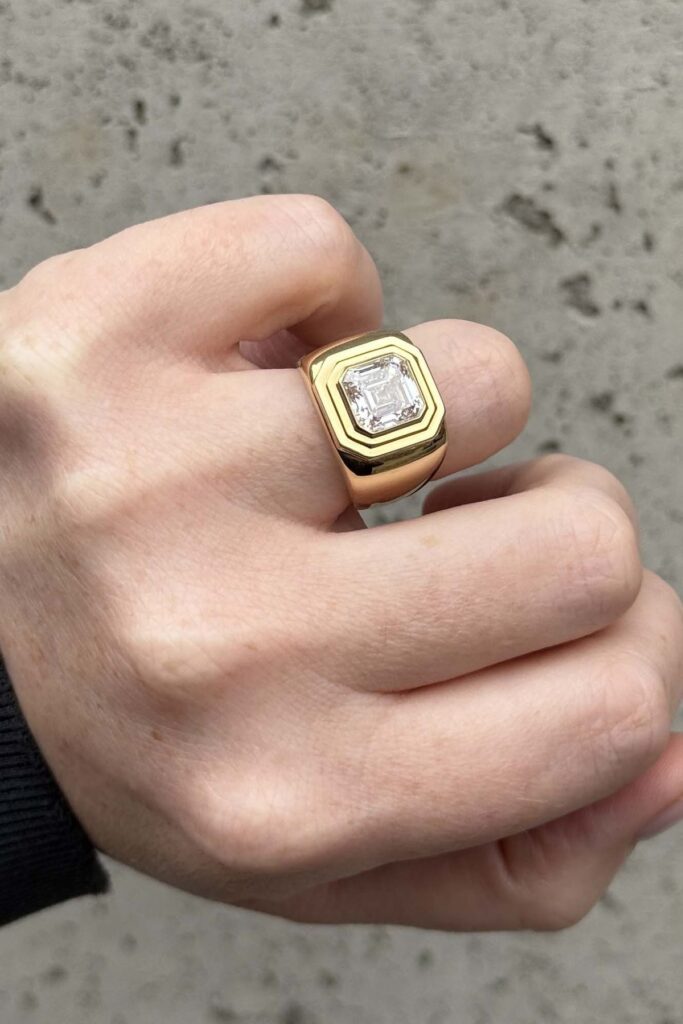 Bold men’s engagement ring with emerald-cut diamond in yellow gold, showcasing statement jewelry for modern men.