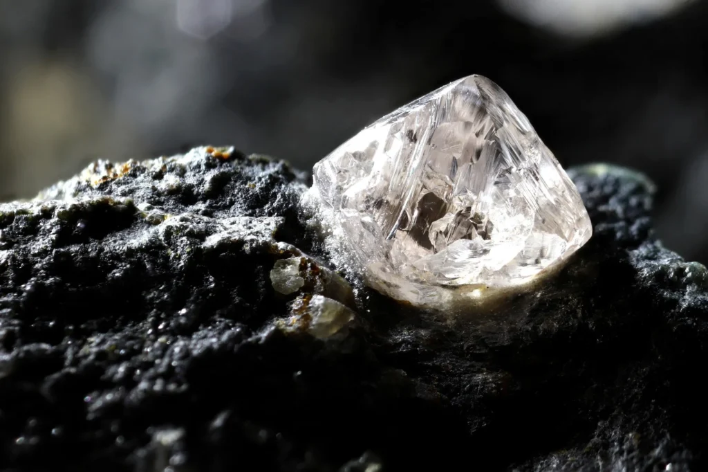 Rough natural diamond embedded in rock, showing how earth-mined diamonds are naturally formed over billions of years.