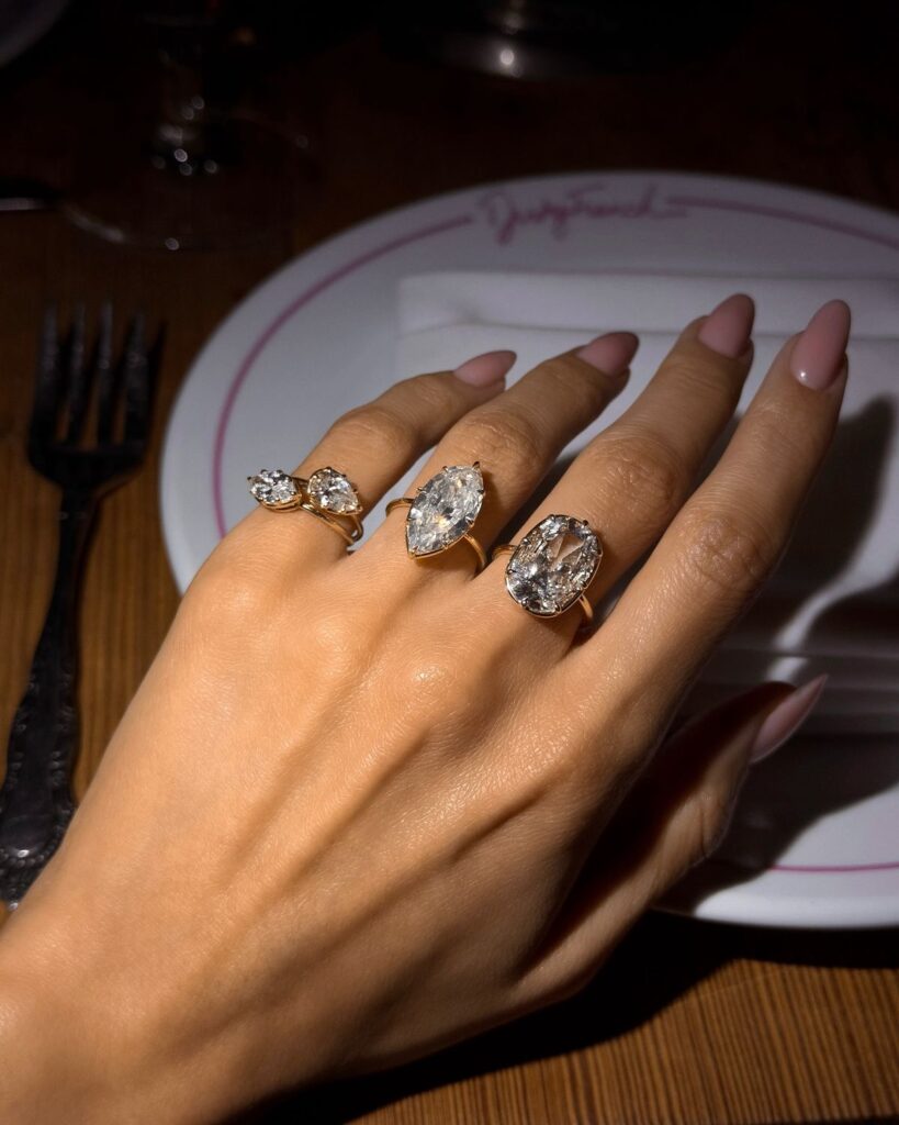 Fashionable hand wearing stacked pinky rings, diamond rings, bracelets, and layered jewelry for a modern luxury look.
