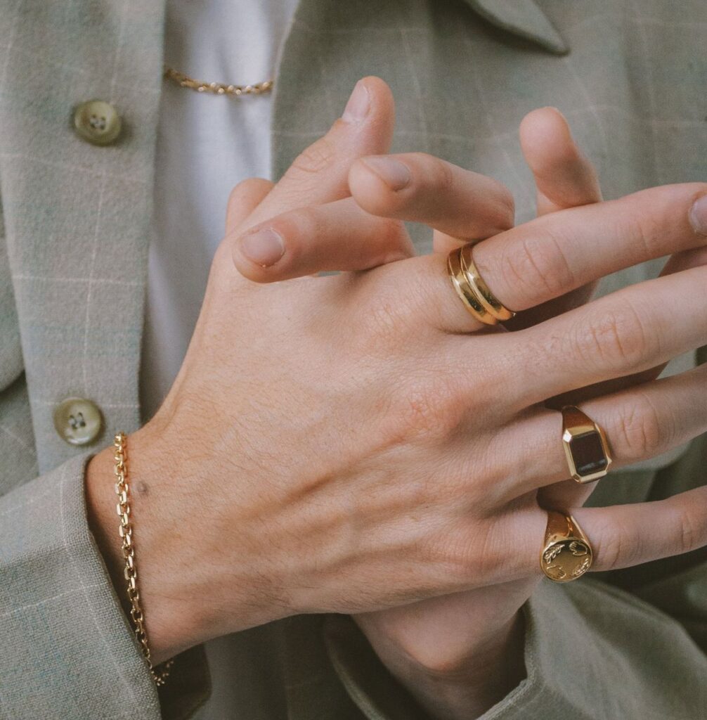 Modern men's jewelry collection featuring signet rings, pearl necklaces, luxury chains, and gemstone accessories.
